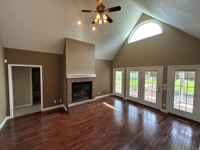 unfurnished living room featuring a ceiling fan, wood-type flooring, a fireplace, high vaulted ceiling, and baseboards