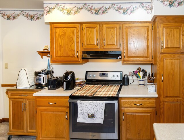 kitchen featuring under cabinet range hood, stainless steel electric stove, light countertops, and brown cabinetry