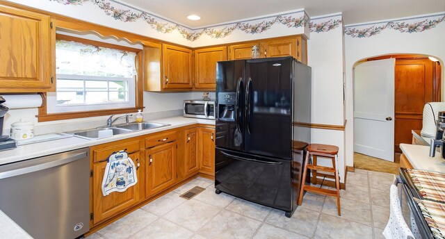 kitchen featuring stainless steel appliances, brown cabinetry, light countertops, and a sink