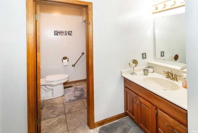 bathroom with toilet, vanity, and baseboards