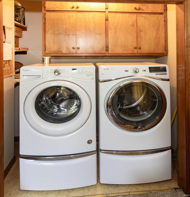 clothes washing area with washer and clothes dryer and cabinet space