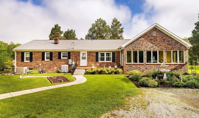 ranch-style home featuring brick siding, a chimney, and a front lawn
