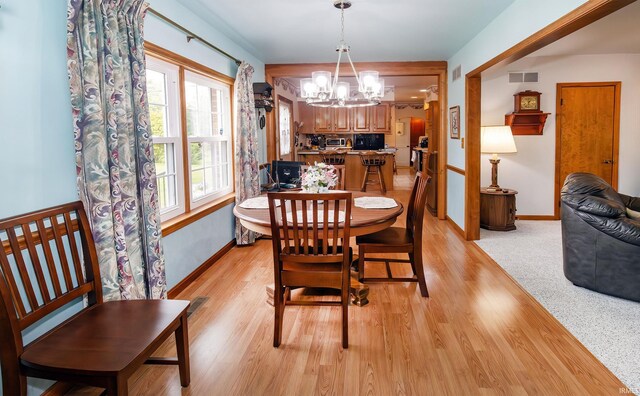 dining area featuring a chandelier, light wood-style floors, and baseboards