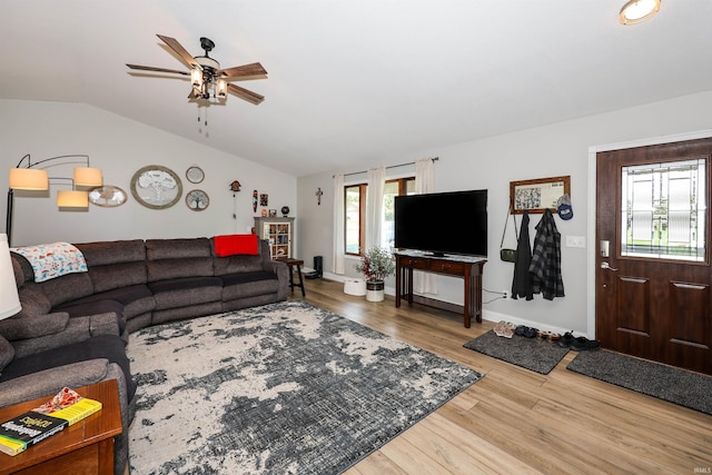 living room featuring wood finished floors, ceiling fan, vaulted ceiling, and baseboards