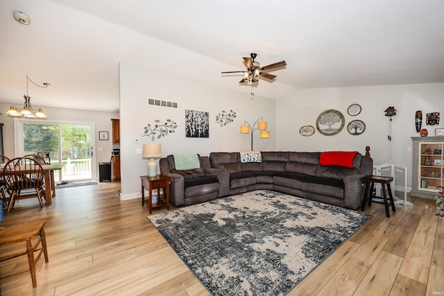 living room featuring ceiling fan, light wood-style floors, lofted ceiling, and a chandelier