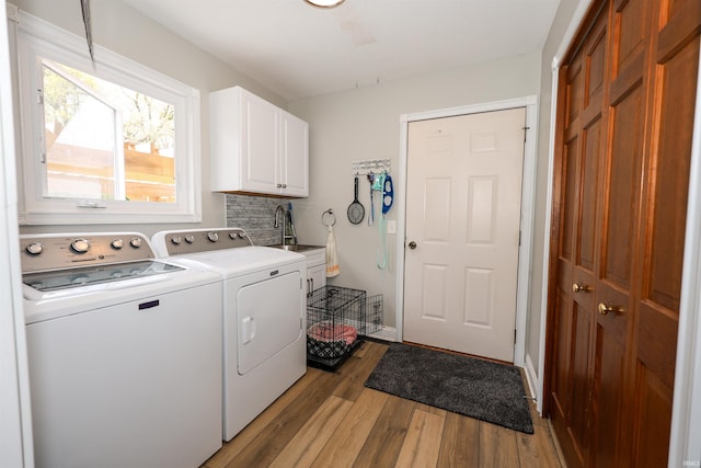 laundry room with cabinet space, washing machine and clothes dryer, and light wood finished floors