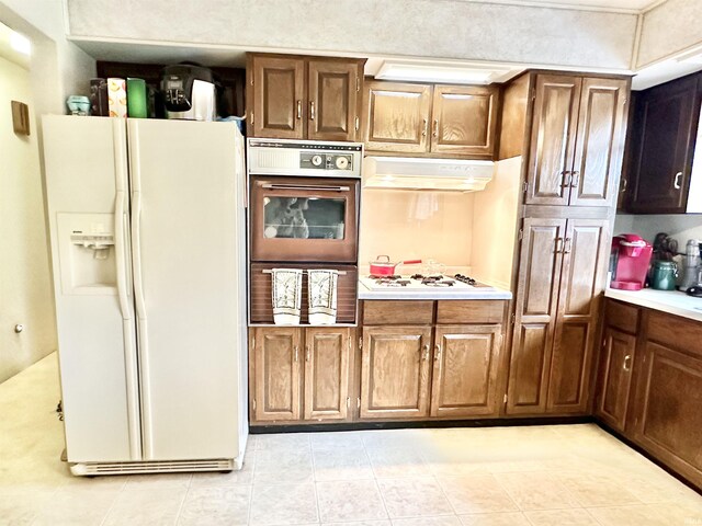 52 S 950 E, Greentown, IN 46936 - kitchen with white appliances, under cabinet range hood, light countertops, light tile patterned floors, and brown cabinets