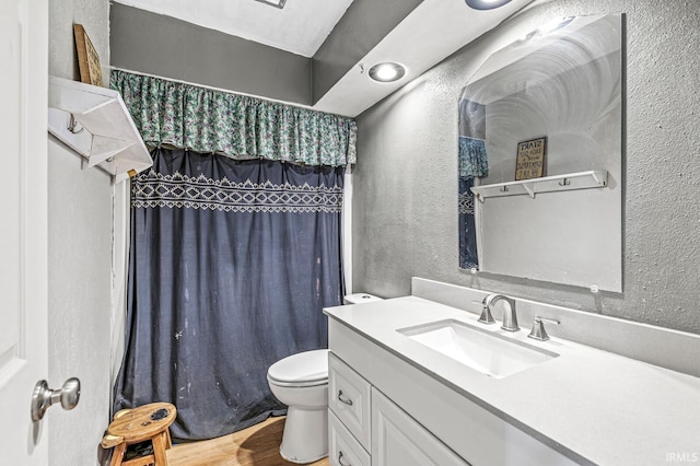 full bathroom featuring a textured wall, toilet, vanity, wood finished floors, and curtained shower
