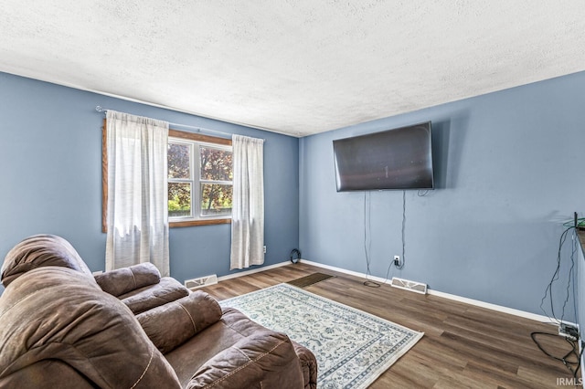 living room featuring a textured ceiling, wood finished floors, and baseboards