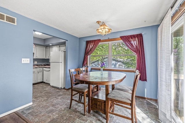 dining room with baseboards, plenty of natural light, a chandelier, and a textured ceiling