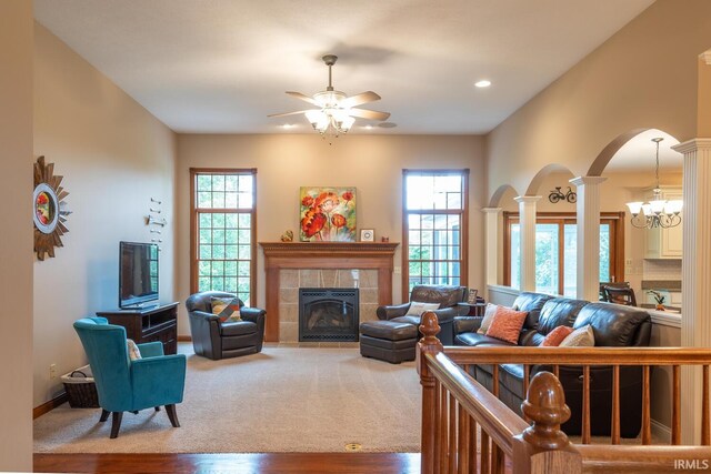 living room featuring ornate columns, arched walkways, ceiling fan, a tile fireplace, and wood finished floors