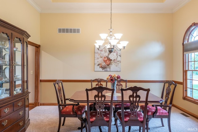 carpeted dining area with a chandelier, crown molding, and baseboards