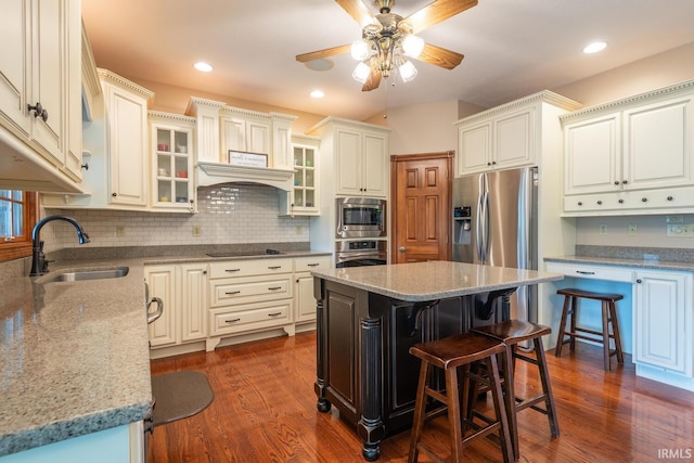 kitchen featuring appliances with stainless steel finishes, a sink, dark wood-type flooring, ceiling fan, and decorative backsplash