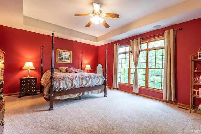 carpeted bedroom with baseboards, ceiling fan, and a tray ceiling