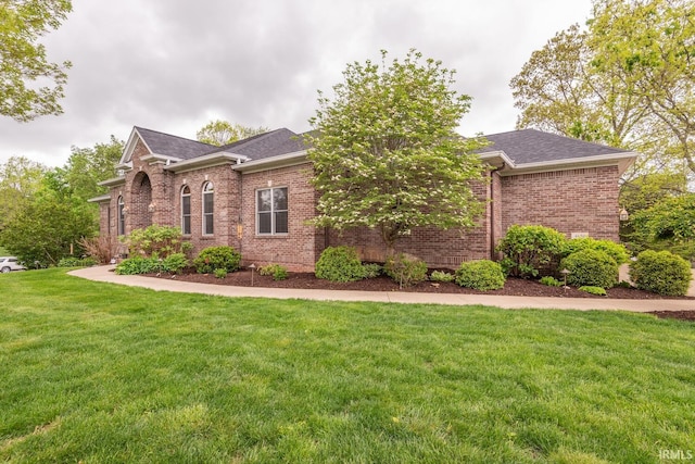 view of front of house with brick siding, a front yard, and roof with shingles