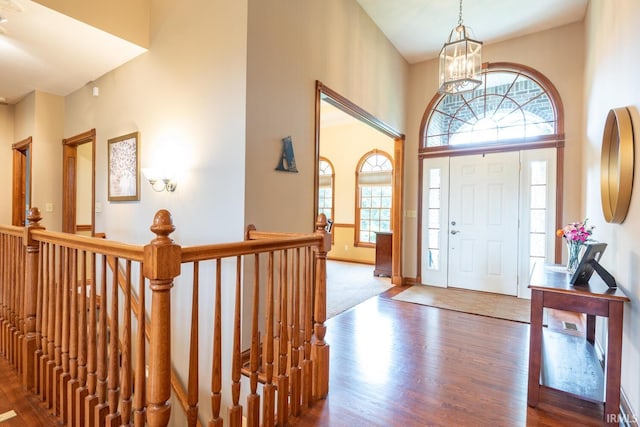 foyer entrance with wood finished floors, a chandelier, a high ceiling, and baseboards