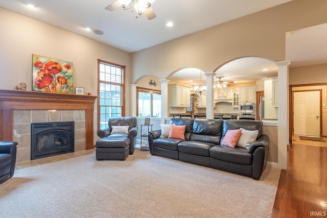 carpeted living area with ornate columns, a ceiling fan, arched walkways, a fireplace, and recessed lighting