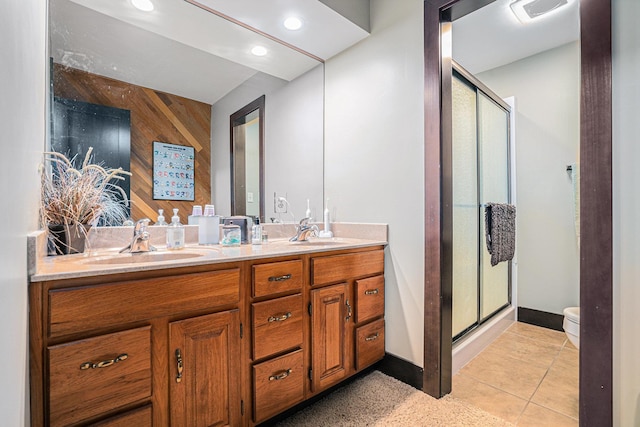 full bathroom with double vanity, a shower stall, toilet, baseboards, and recessed lighting