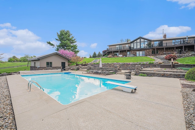 outdoor pool with a patio area, a lawn, a diving board, and a wooden deck