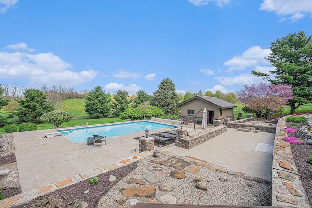 outdoor pool with a patio area and a diving board