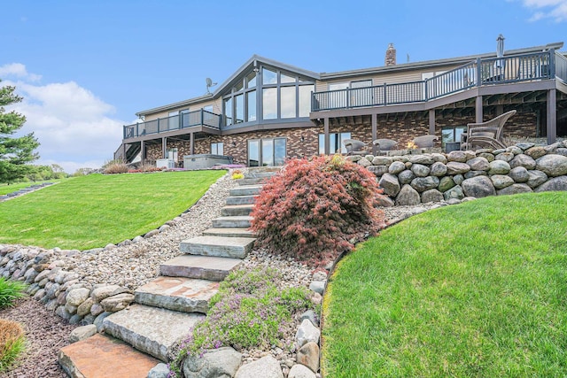 rear view of house featuring a wooden deck, a lawn, brick siding, and a chimney