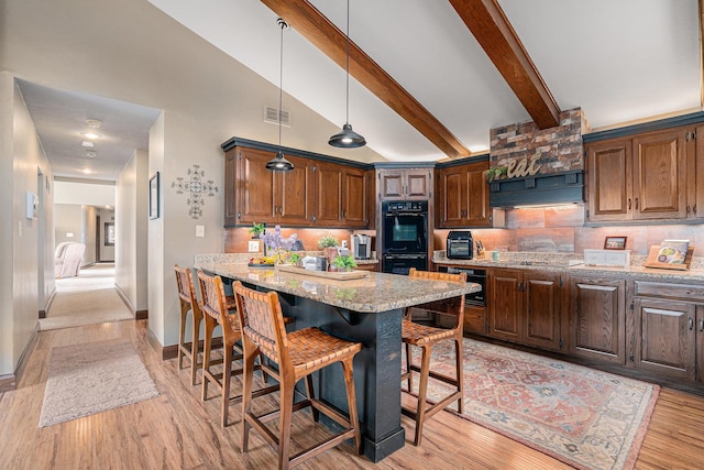 kitchen featuring a breakfast bar, decorative backsplash, light stone counters, beam ceiling, and hanging light fixtures
