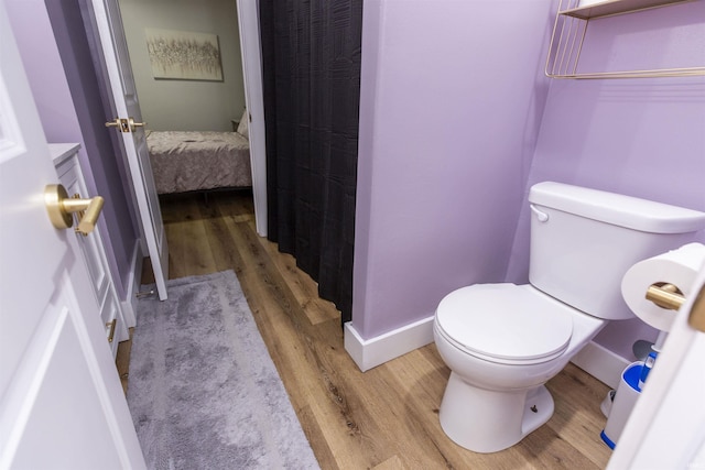 bathroom featuring wood finished floors, toilet, baseboards, and curtained shower