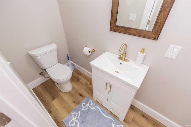 bathroom with toilet, wood finished floors, vanity, and baseboards