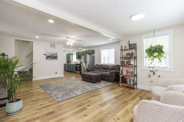 living area featuring baseboards, light wood-type flooring, a ceiling fan, and recessed lighting