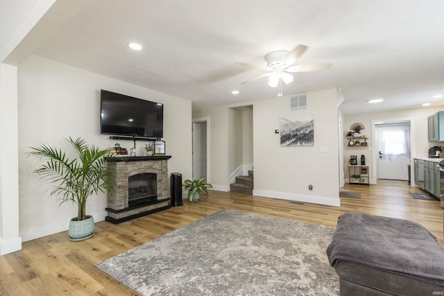 living room featuring stairs, light wood-style flooring, a ceiling fan, baseboards, and recessed lighting