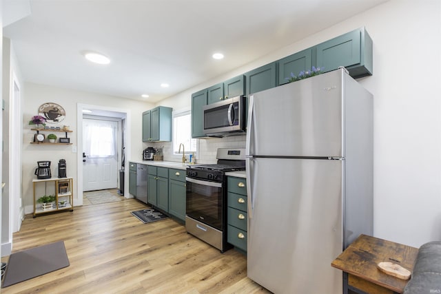kitchen featuring appliances with stainless steel finishes, light wood finished floors, light countertops, tasteful backsplash, and recessed lighting