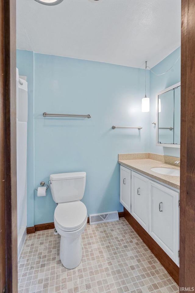 bathroom featuring baseboards, vanity, a shower, and toilet