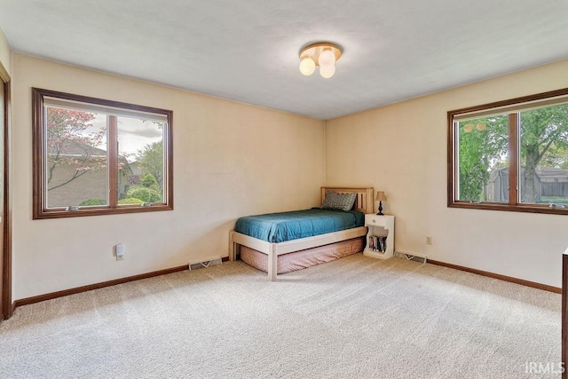 carpeted bedroom featuring multiple windows and baseboards