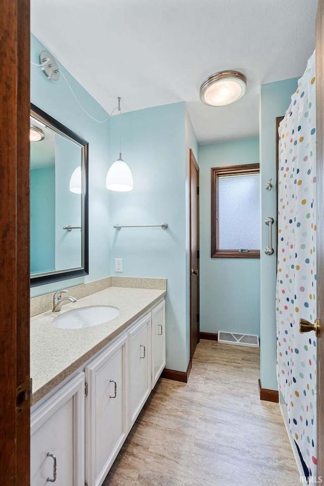 bathroom with wood finished floors, vanity, baseboards, and a shower with curtain