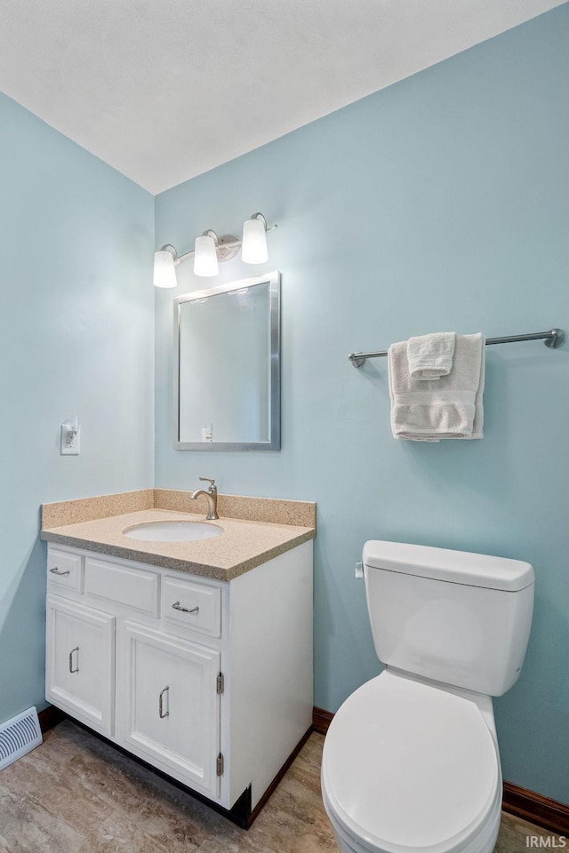 half bath featuring vanity, baseboards, and toilet