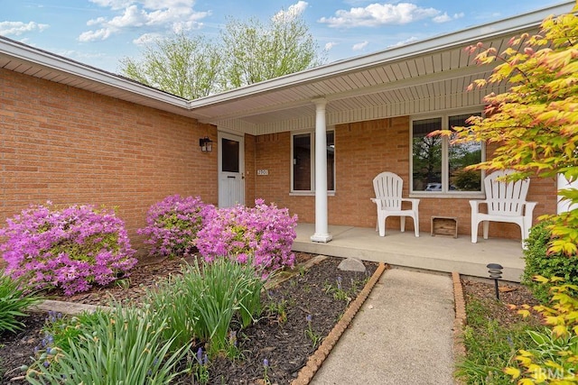 property entrance featuring a porch and brick siding