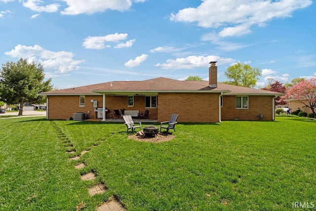 rear view of property with an outdoor fire pit, central AC, a yard, and a chimney