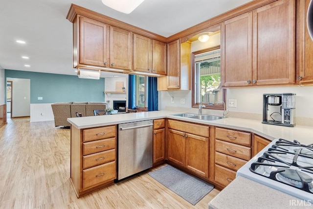 kitchen featuring dishwasher, a peninsula, open floor plan, light countertops, and light wood-style flooring