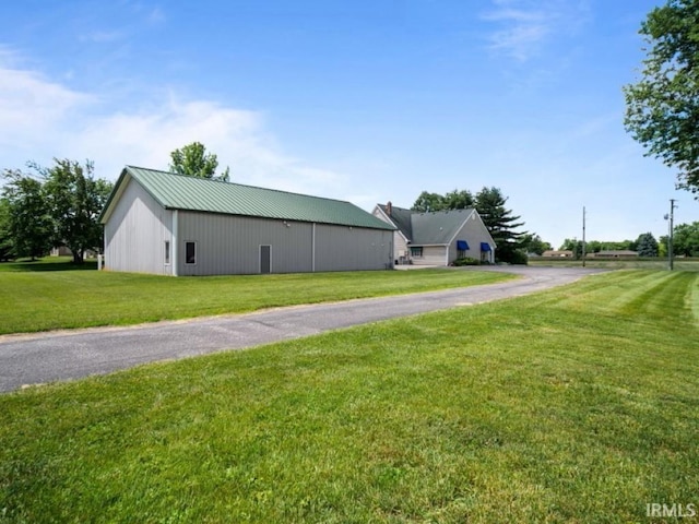 view of side of property featuring a lawn, a pole building, an outbuilding, and metal roof