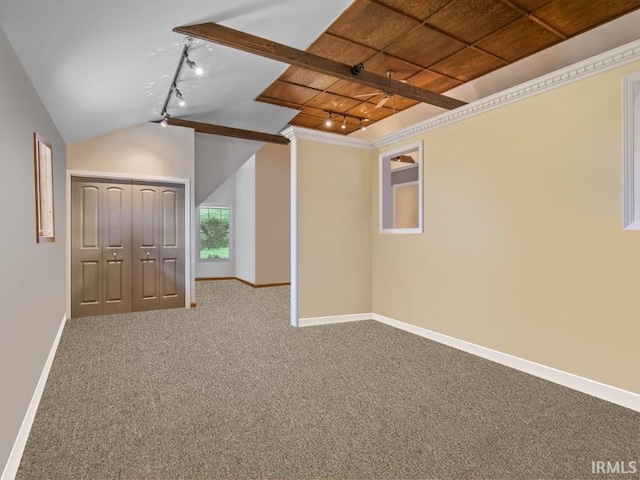 carpeted spare room featuring rail lighting, baseboards, and vaulted ceiling