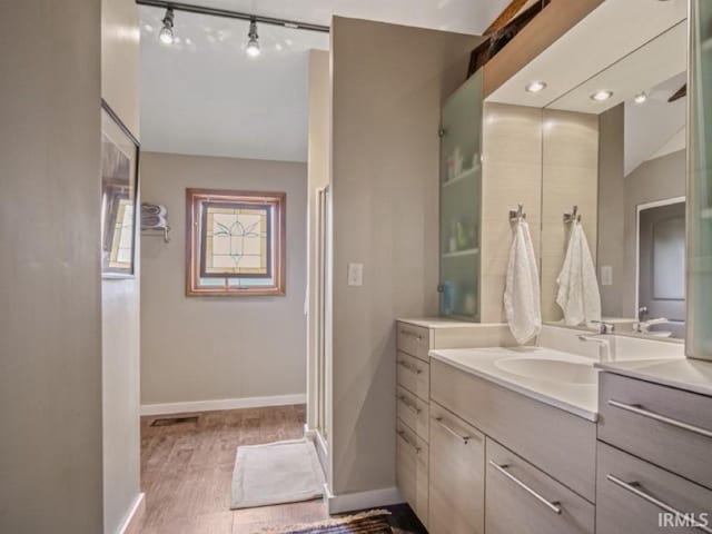 full bathroom with vanity, wood finished floors, baseboards, track lighting, and vaulted ceiling