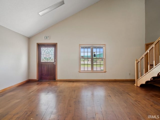 foyer with high vaulted ceiling, hardwood / wood-style floors, stairs, and baseboards
