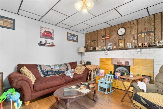 510 W Washington St, Oakland City, IN 47660 - living room featuring wood finished floors, a paneled ceiling, wooden walls, and a brick fireplace