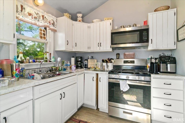 510 W Washington St, Oakland City, IN 47660 - kitchen with appliances with stainless steel finishes, a sink, light countertops, white cabinetry, and vaulted ceiling