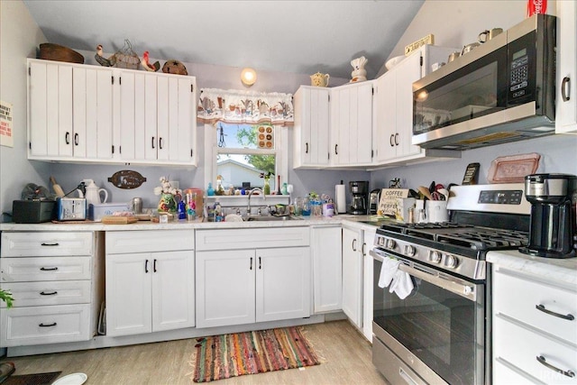 510 W Washington St, Oakland City, IN 47660 - kitchen with appliances with stainless steel finishes, a sink, light wood-style flooring, light countertops, and vaulted ceiling
