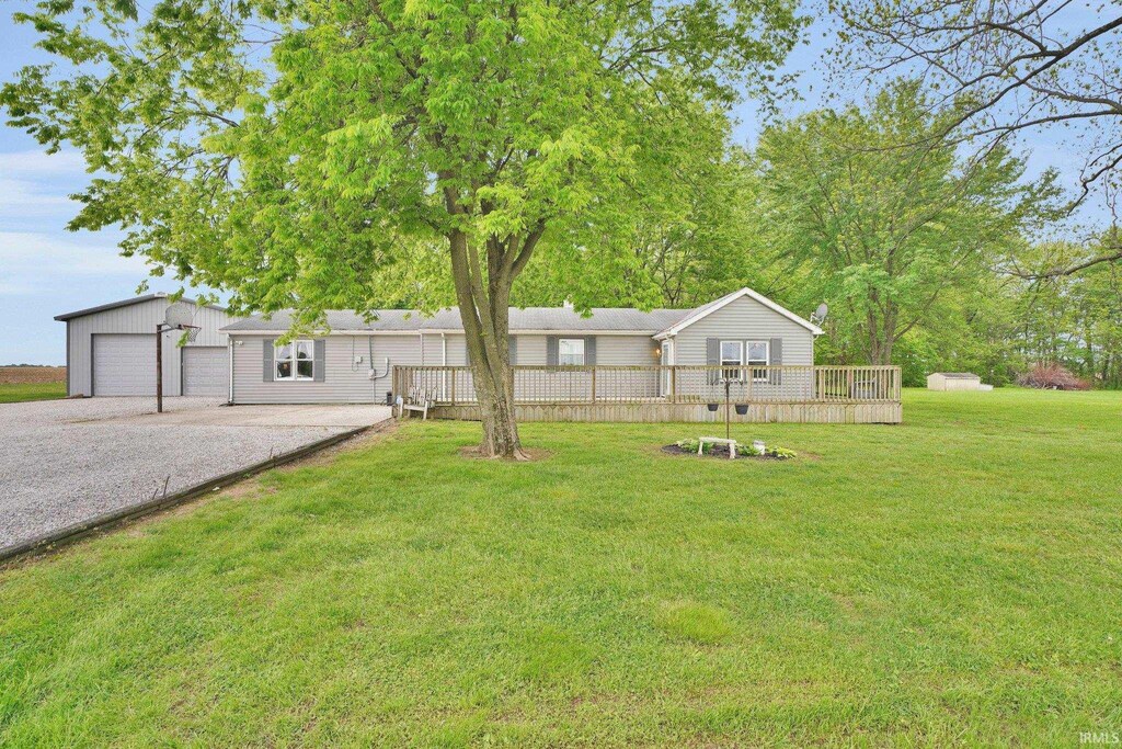 view of green lawn featuring a wooden deck and a detached garage