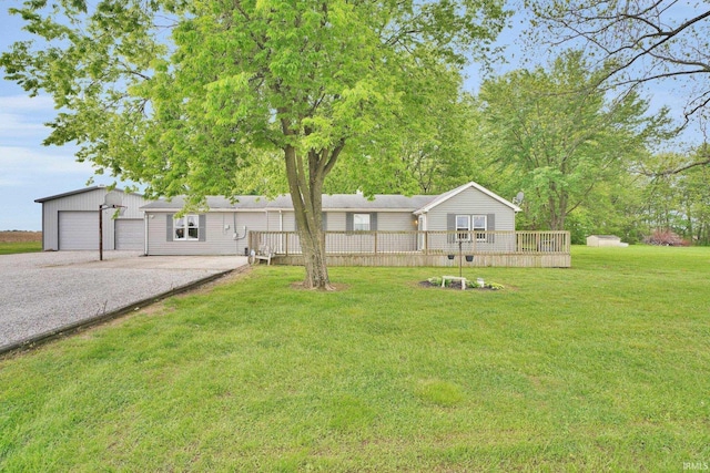 view of green lawn featuring a wooden deck and a detached garage