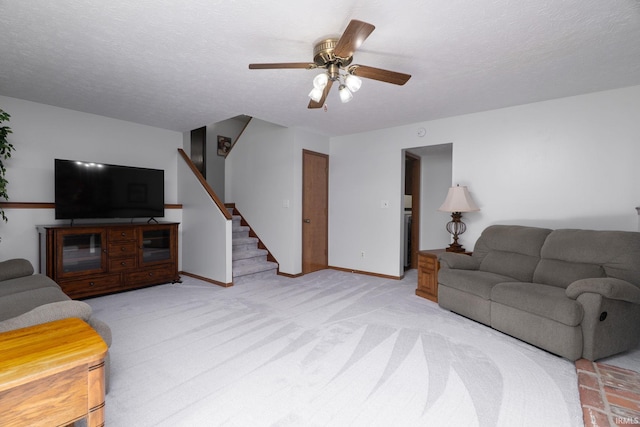 living room featuring stairs, a ceiling fan, light carpet, and baseboards