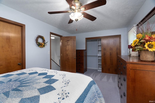 carpeted bedroom with a textured ceiling, a closet, and ceiling fan