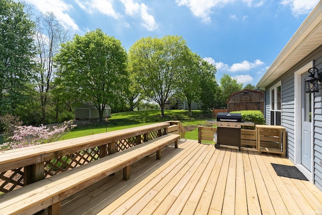 wooden deck featuring a grill, a storage shed, a lawn, and an outbuilding